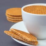 Close-up image of a coffee cup with stroopwafels on a saucer, perfect for food photography enthusiasts.